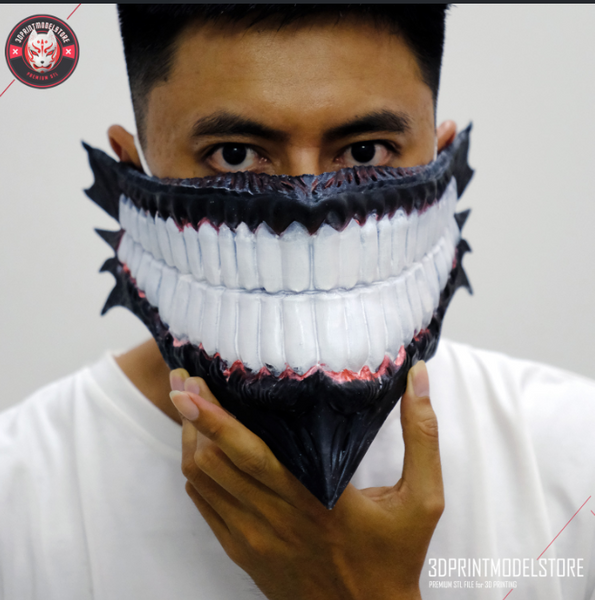 A man holding a 3D printed cosplay mask with gigantic white teeth dark upper skin.