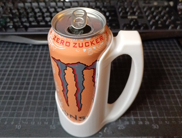 A 3D-printed handle attachment for holding a 500ml can, shown with a can of energy drink fitted securely in the handle.