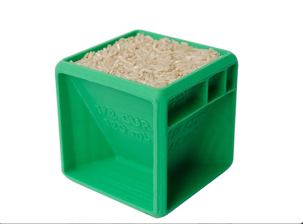 A green 3D-printed measuring cube, filled with rice, showing different measurement marks for accurate kitchen measurements.