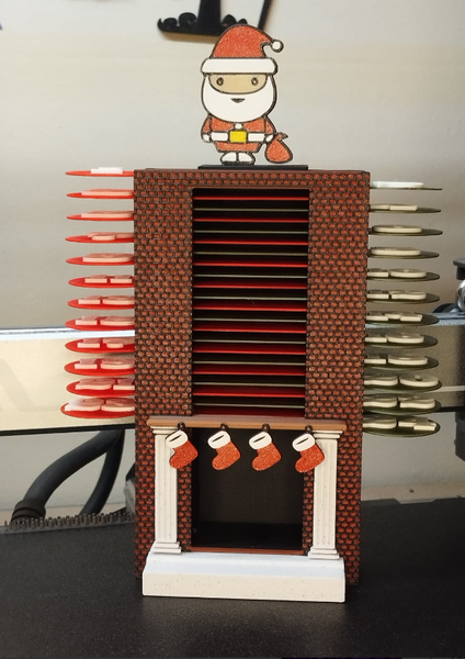 A 3D-printed Christmas Advent Calendar designed as a brick fireplace with stockings and a Santa figurine on top, with slots for treats.