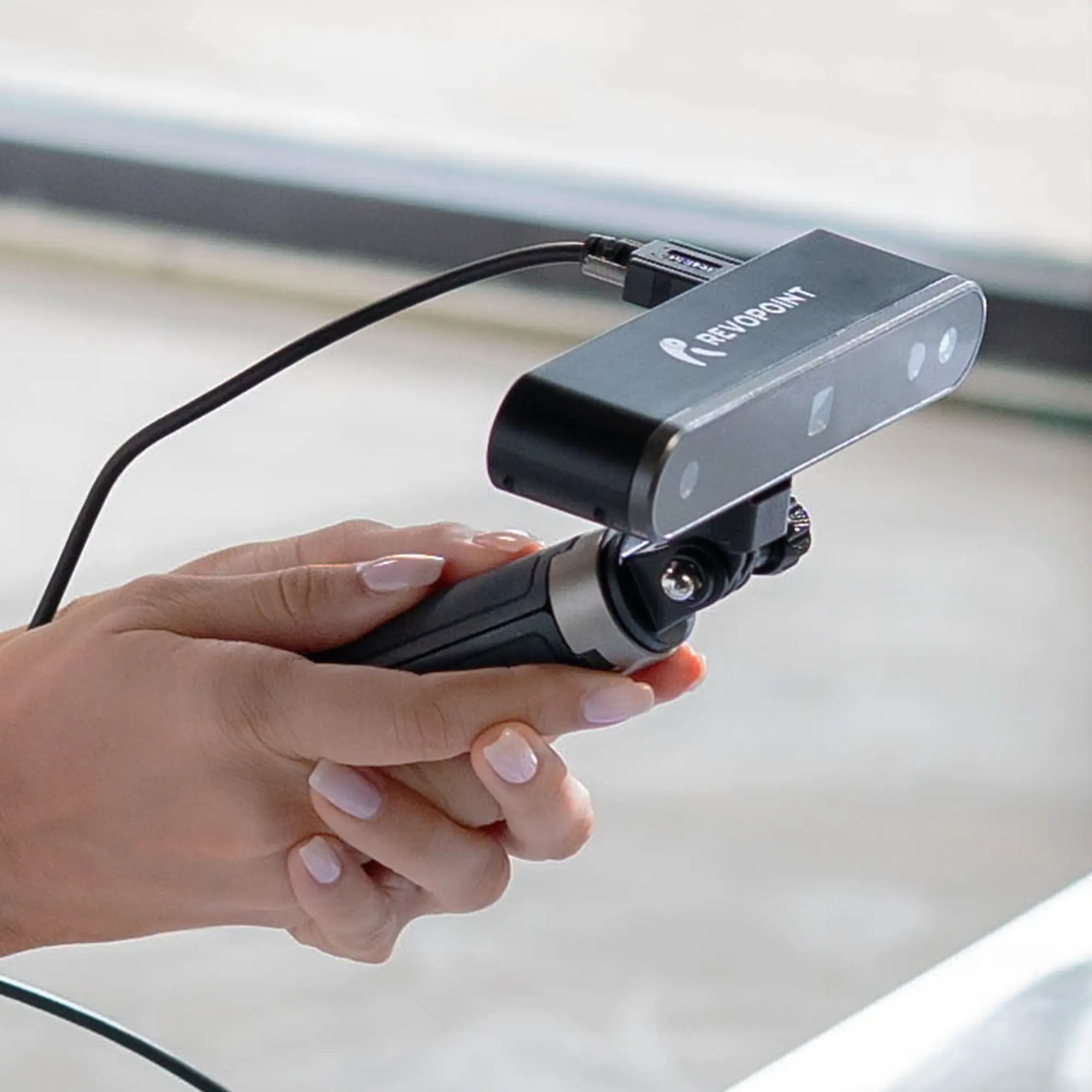 Hand holding a Revopoint 3D scanner during the first step of the 3D scanning to printing process.