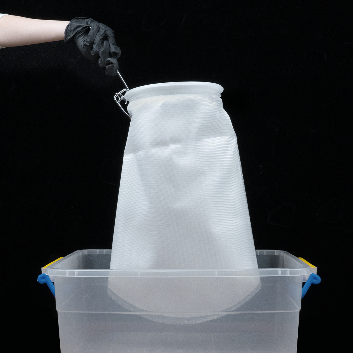 Phrozen Alcohol Filter Bag hung on a plastic container, showing a simple setup for alcohol filtration.