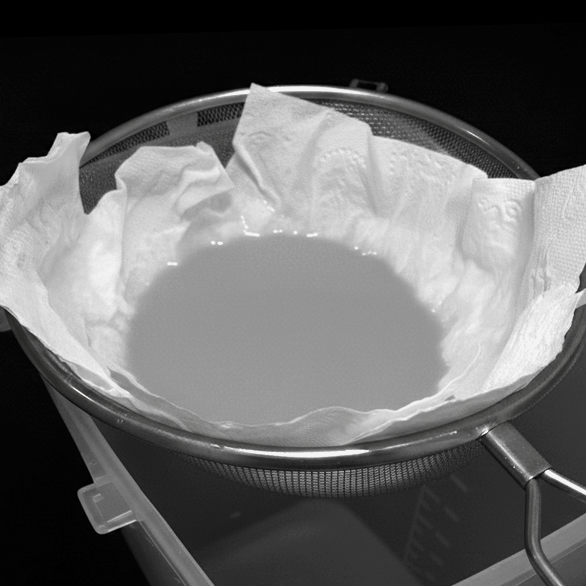Used alcohol being strained through a cloth filter, representing an attempt to reuse alcohol without a reliable filtration method.