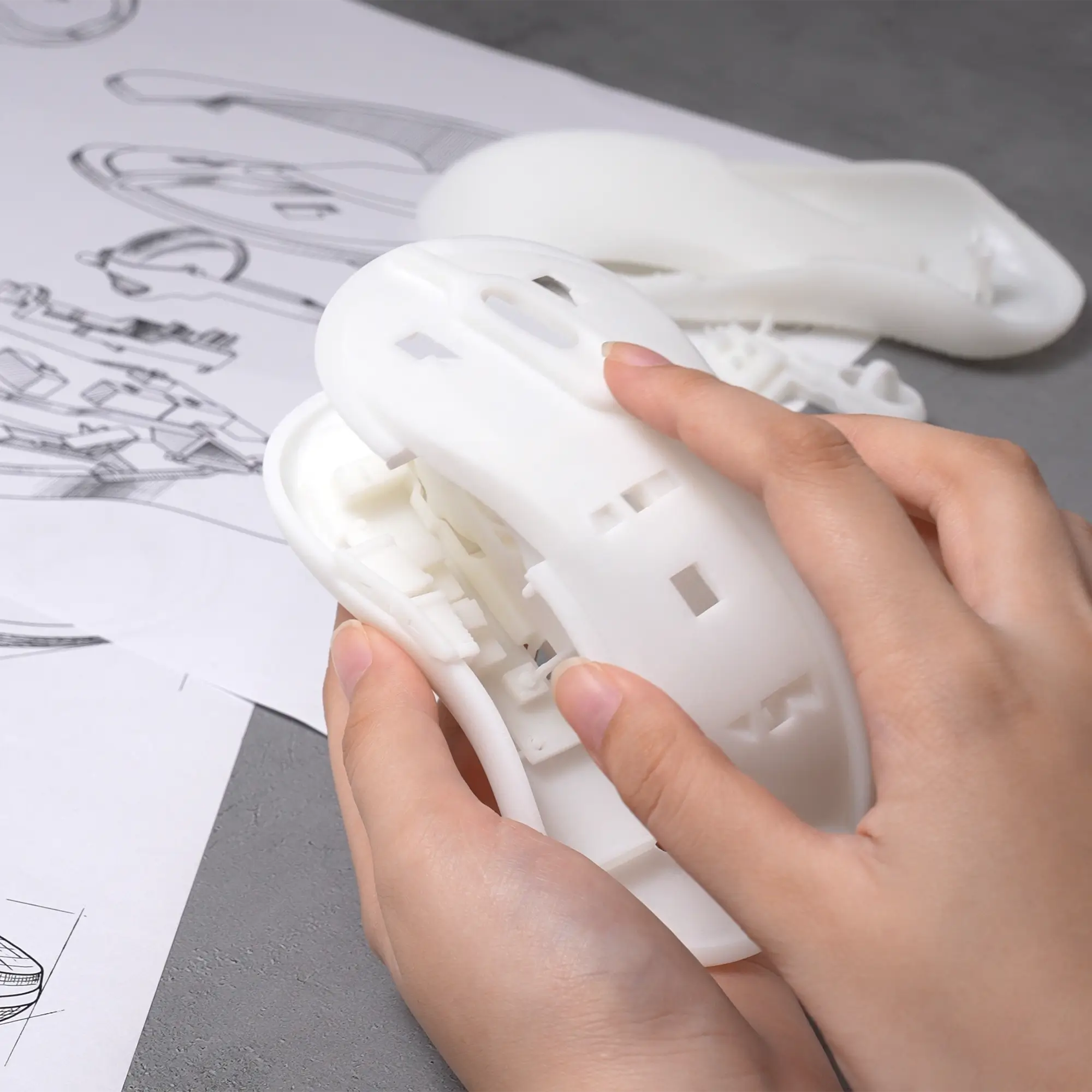 Hands holding a white prototype mouse printed with Phrozen ProtoWhite Tough Resin for rapid prototyping and design review.