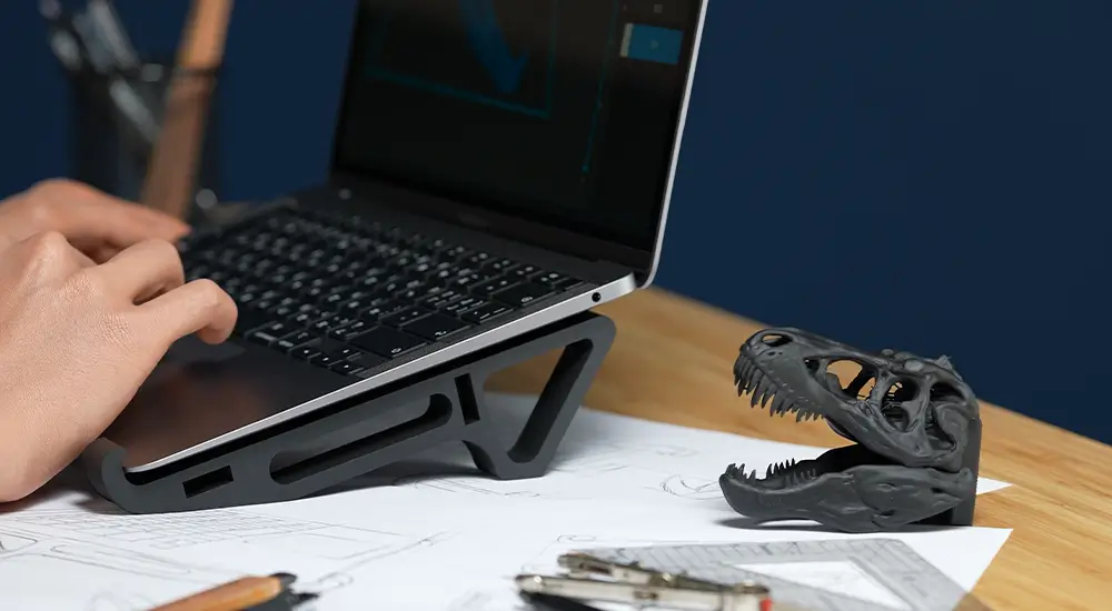 Laptop stand and dinosaur model printed with Phrozen x Loctite ONYX Rigid Pro410, highlighting rigid and reliable DIY prints.